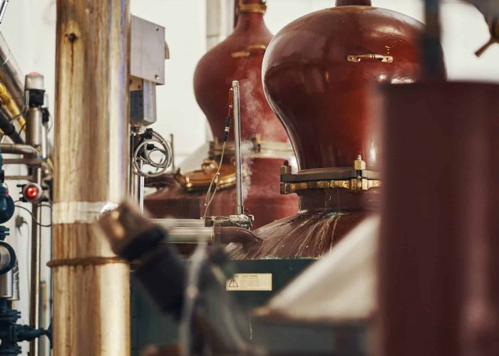 distillation-1 Copper pot stills inside the Rozelieures distillery, where heat and distillation equipment are used to transform fermented mash into French single malt whisky.