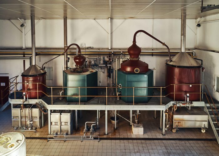 distillation-4 Copper pot stills inside the Rozelieures distillery, where heat and distillation equipment are used to transform fermented mash into French single malt whisky.